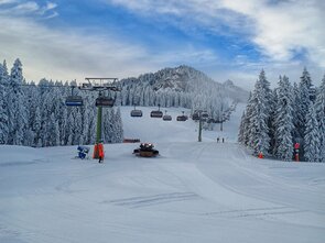Winter landscape featuring ski lifts, snow, and trees.