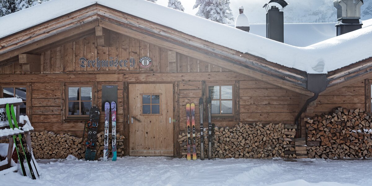 Eine Berghütte im Schnee mit Skiern und Holzlager.
