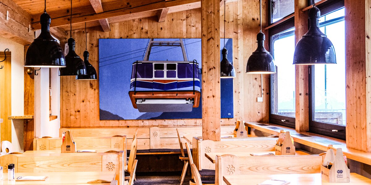 Holzinterieur mit Tischen und einer Seilbahn-Grafik an der Wand.