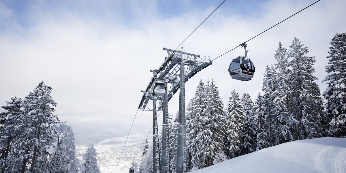 Seilbahn-Kabine über verschneiten Bäumen in den Bergen.