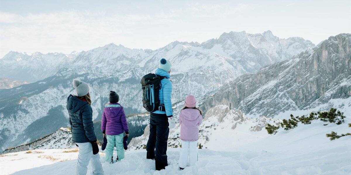 Blick auf Familienmitglieder in Winterkleidung in schneebedeckter Landschaft.