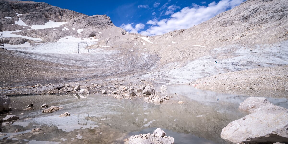 Blick auf eine Gletscherlandschaft mit Schmelzwasser-See und Felsen.