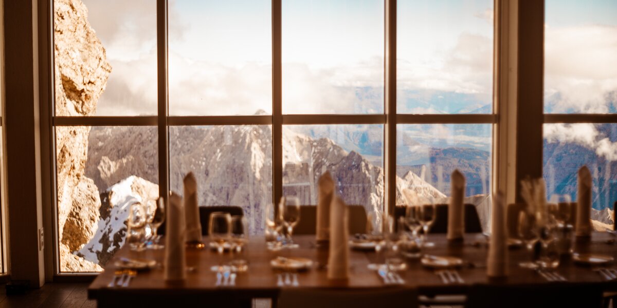 A beautifully set table with glasses, cutlery, napkins, and a view of majestic mountains.