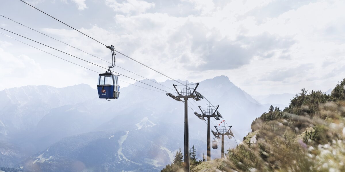 Blick auf eine Gondelbahn in den Bergen und weite Landschaft.