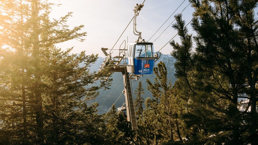 Eine Seilbahn mit Blick auf Berge und Bäume im Sonnenlicht.