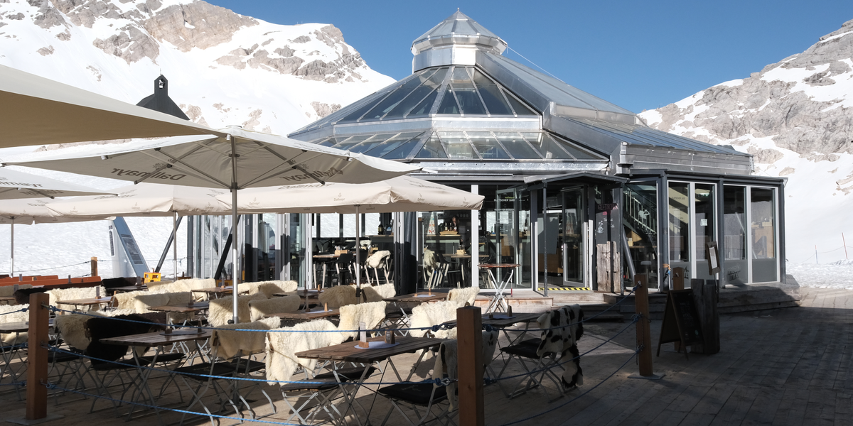 Ein gläsernes Restaurant in schneebedeckter Berglandschaft.