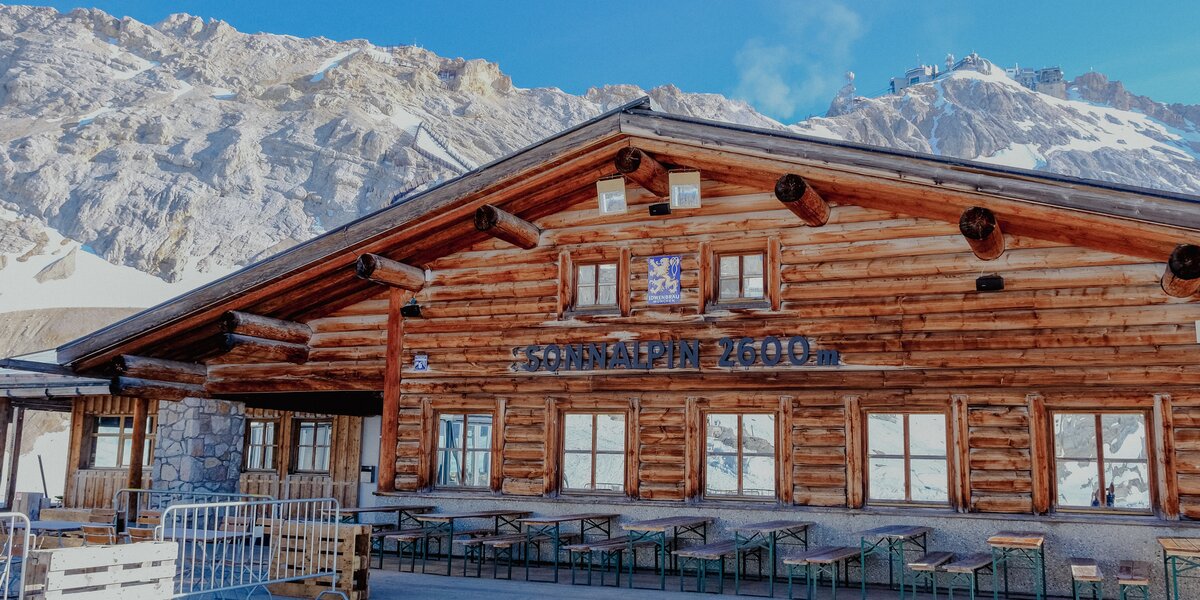 The Sonnalpin lodge in the mountains with outdoor seating and tables.