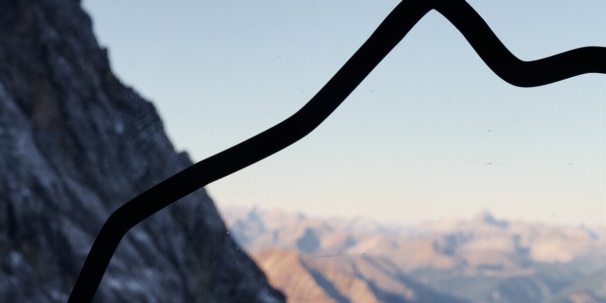 View of a mountain with a stylized cross in the foreground.