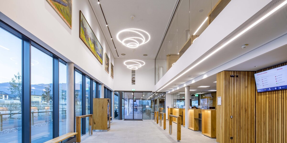 Helle Empfangshalle mit Holz und großen Fenstern sowie Kunstwerken.