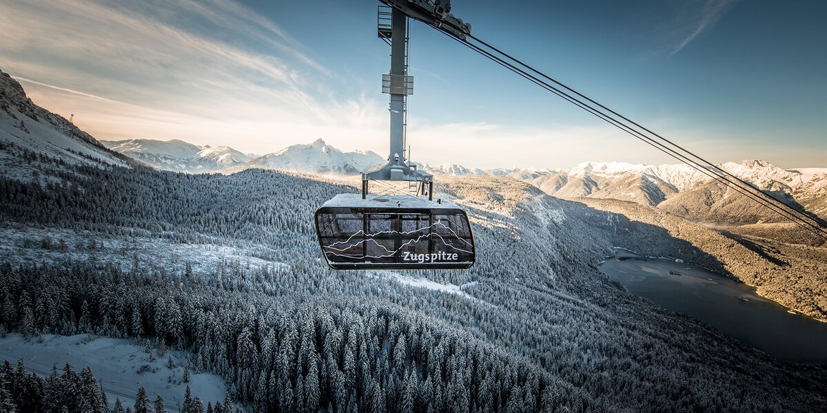 A cable car glides over snow-covered mountains to Zugspitze.