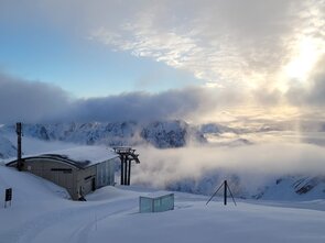 View of a mountain station in a snowy landscape under clouds.
